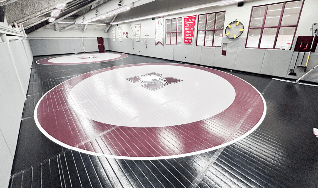 A room with a padded wrestling floor featuring McMaster Marauder logos.